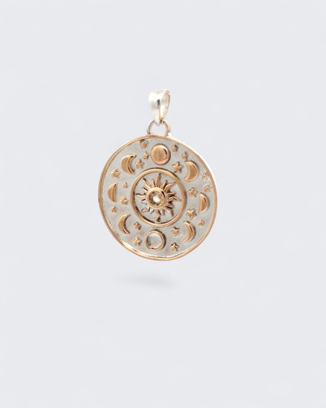 Celestial Sun Moon Phases Pendant at a slight angle showing raised bronze sun, moon phases, and stars on silver-plated disc