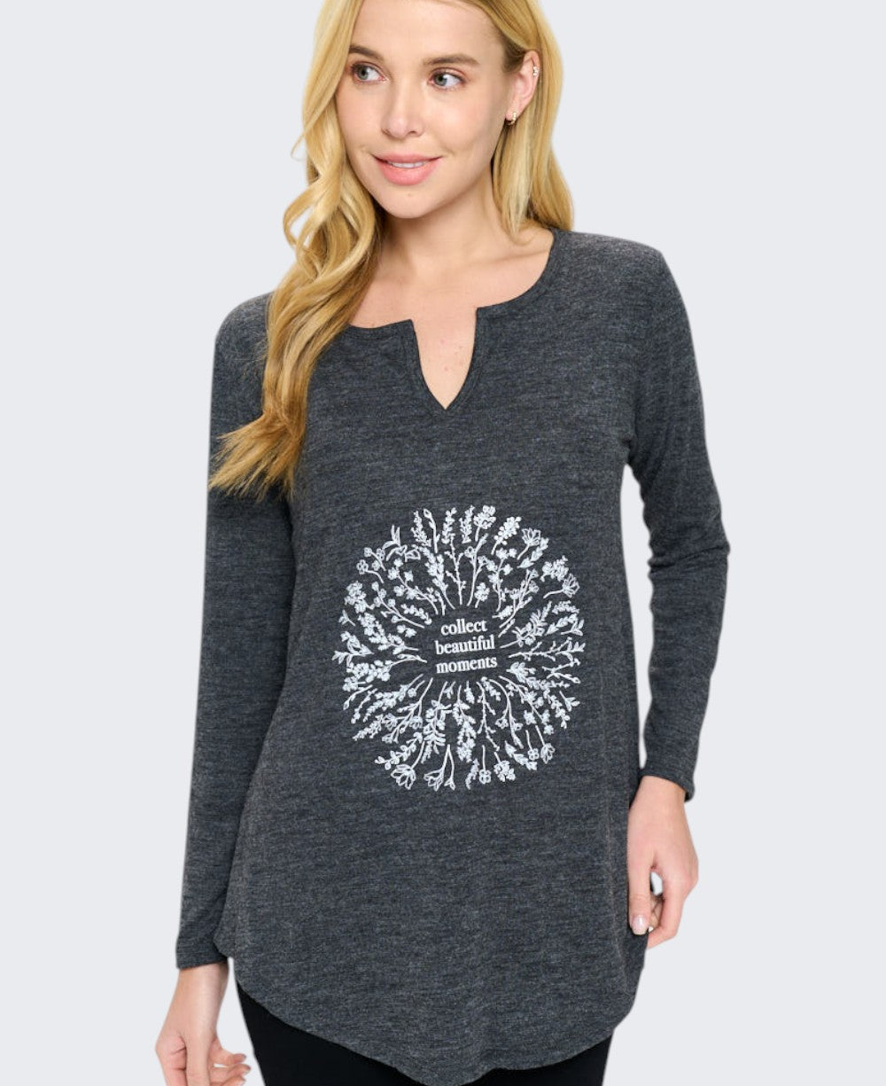 Front detail view of charcoal grey long sleeve tunic top highlighting the white botanical floral wreath graphic and split neckline
