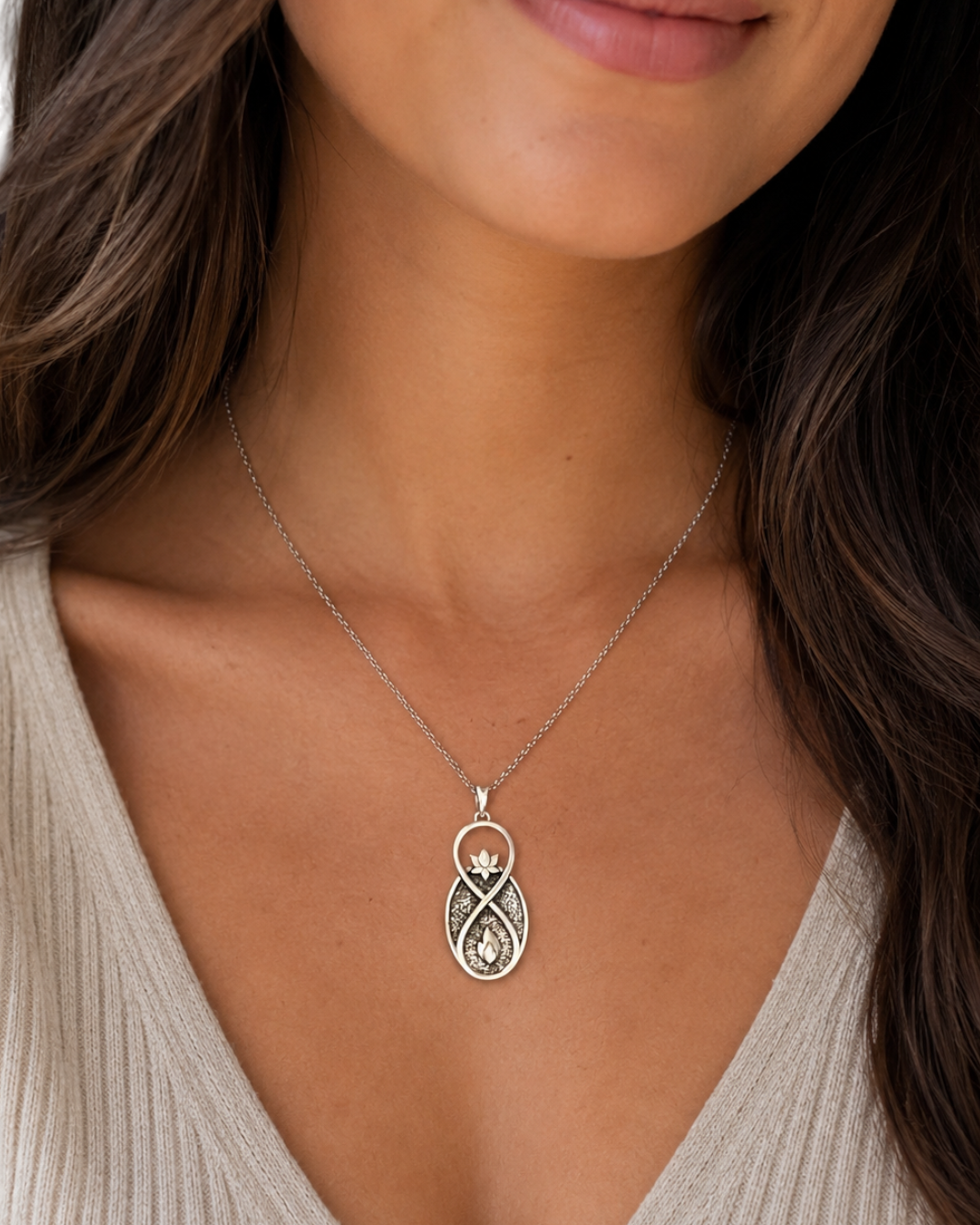 Infinite Lotus Flame Pendant silver necklace worn on woman's neckline, shown on a silver chain against a neutral knit top