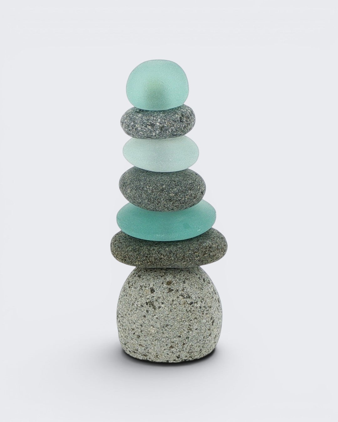 Single tall mini stacked stone cairn with seven alternating grey speckled stones and teal sea glass pieces, front view