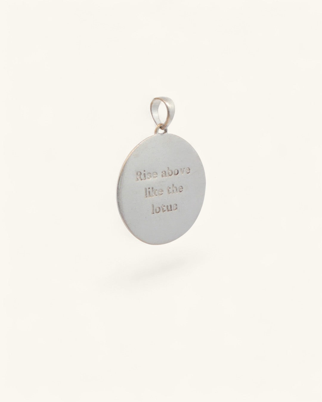 Back of moon wave lotus pendant with engraved mantra reading 'Rise above like the lotus' on smooth silver surface