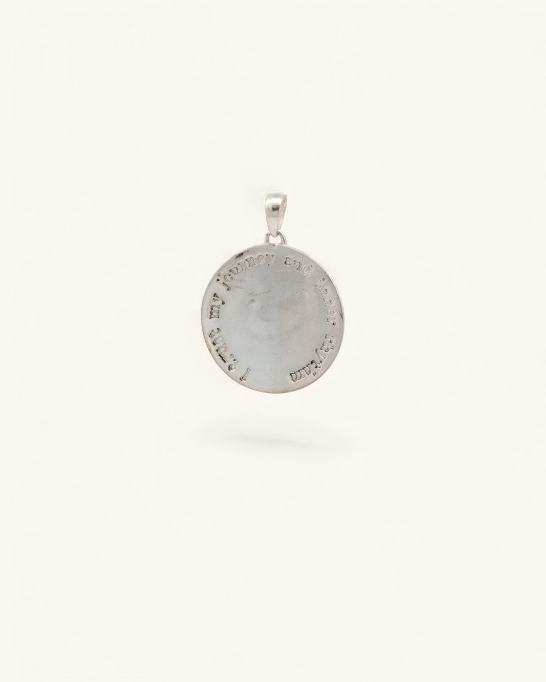 Back of silver crescent moon pendant showing engraved affirmation text circling the rim of the round disc