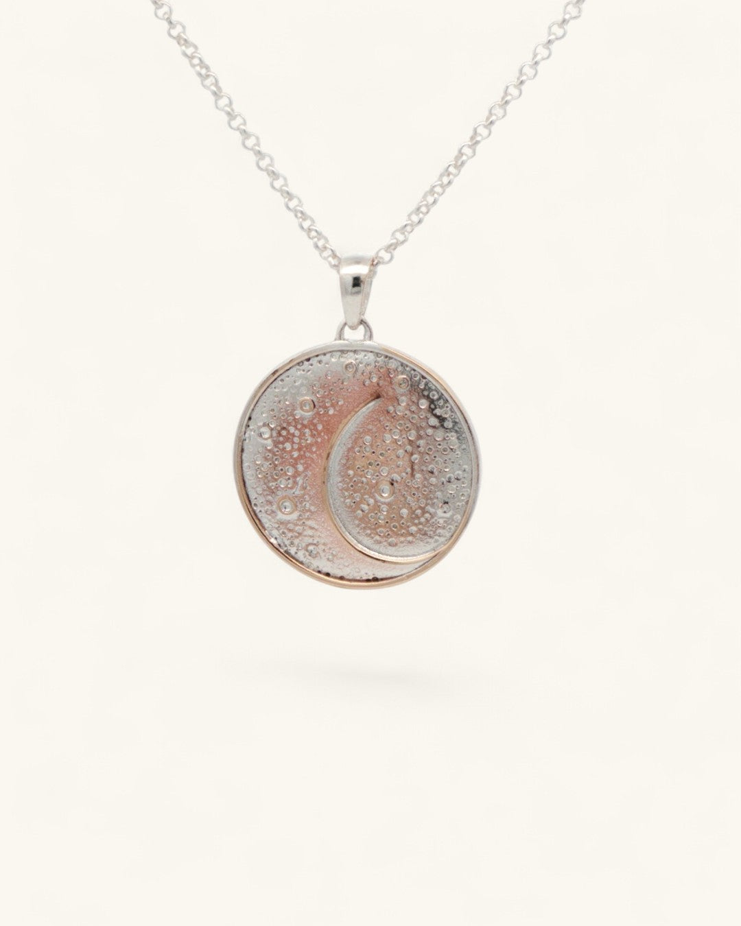 Silver-plated celestial crescent moon pendant hanging on a silver rolo chain against a light background