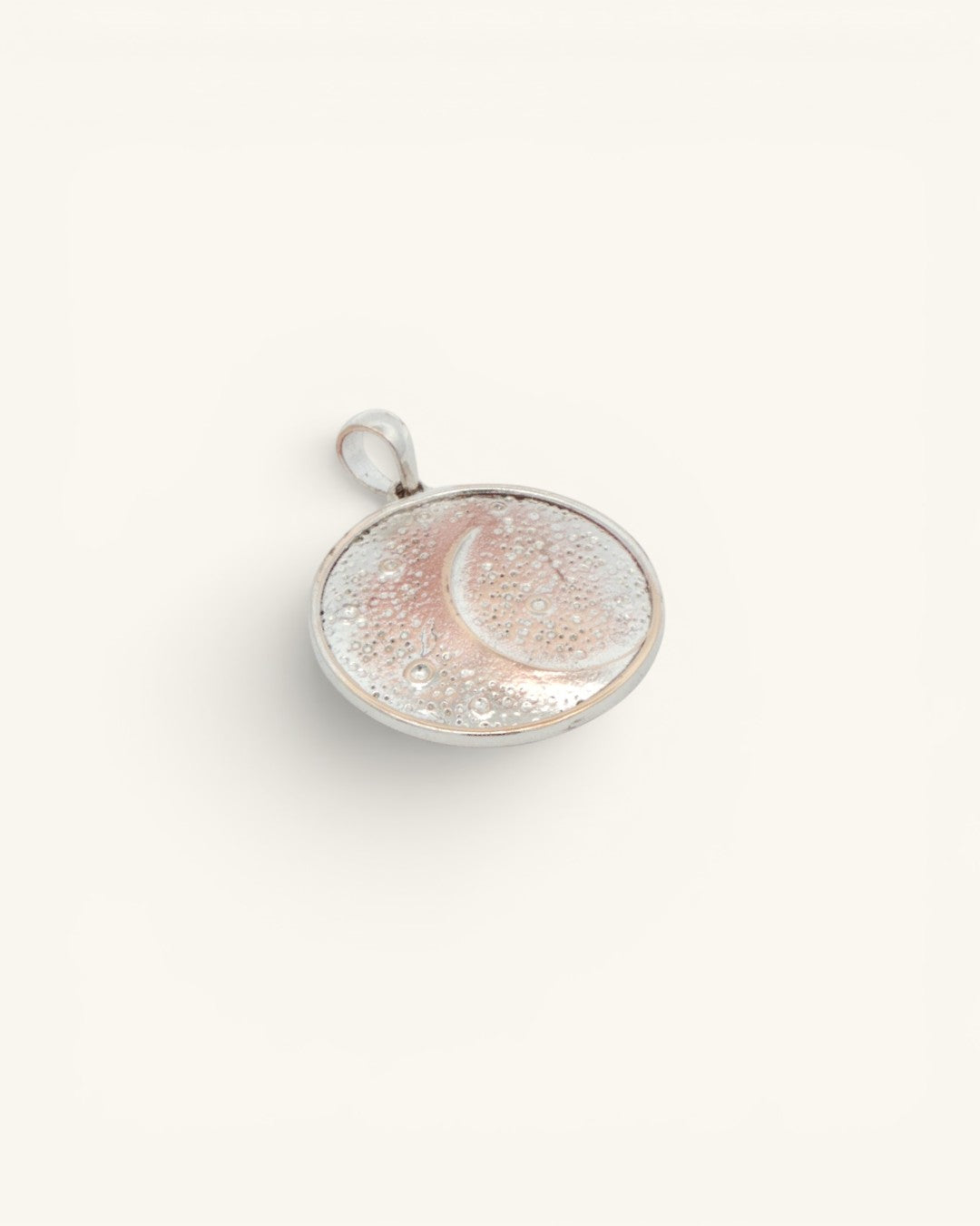 Silver-plated crescent moon pendant shown at a slight side angle, revealing the round disc profile and bezel edge
