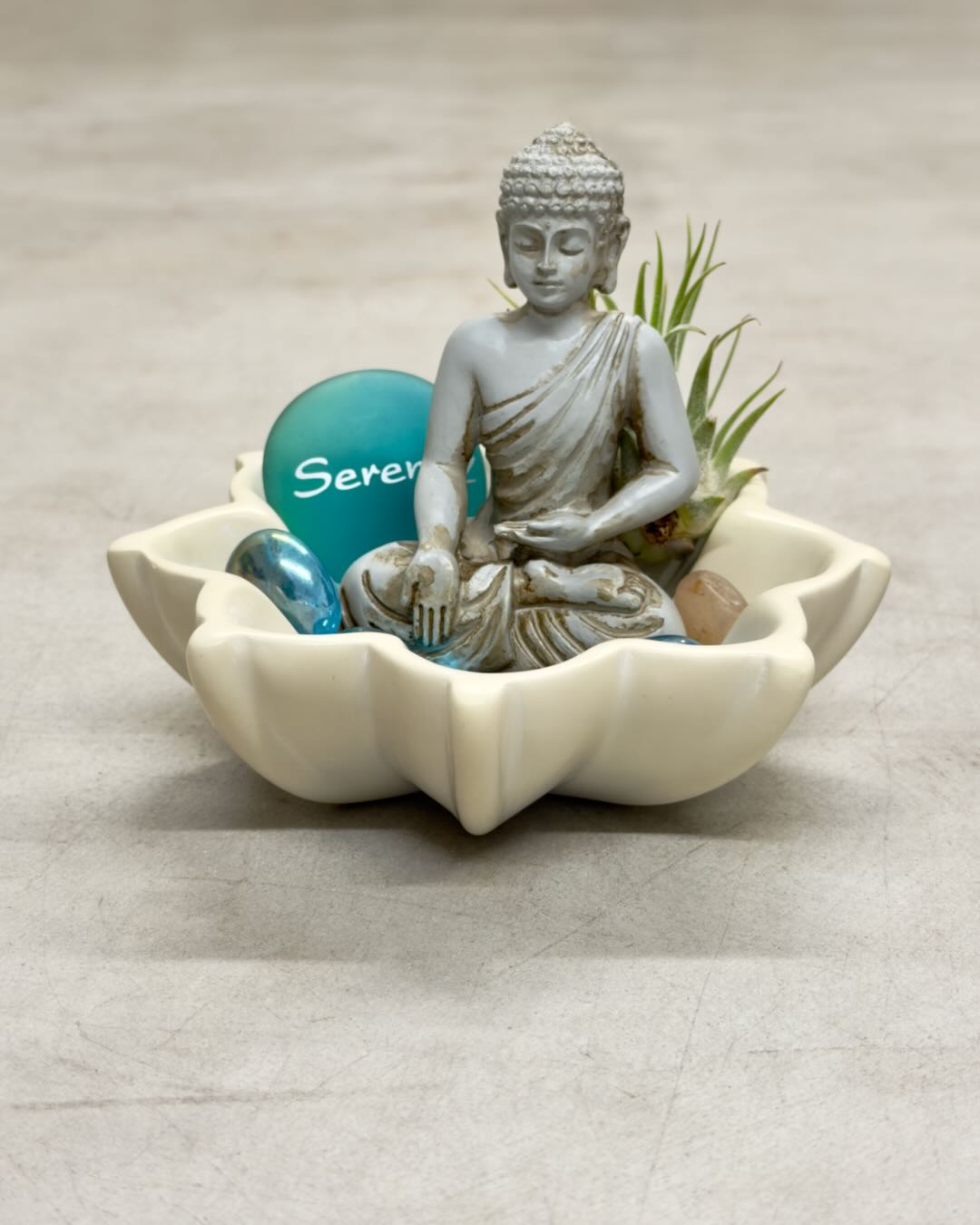 Zen Buddha terrarium in cream lotus soapstone bowl with teal Serenity stone, blue glass marbles, and live air plant, front angle
