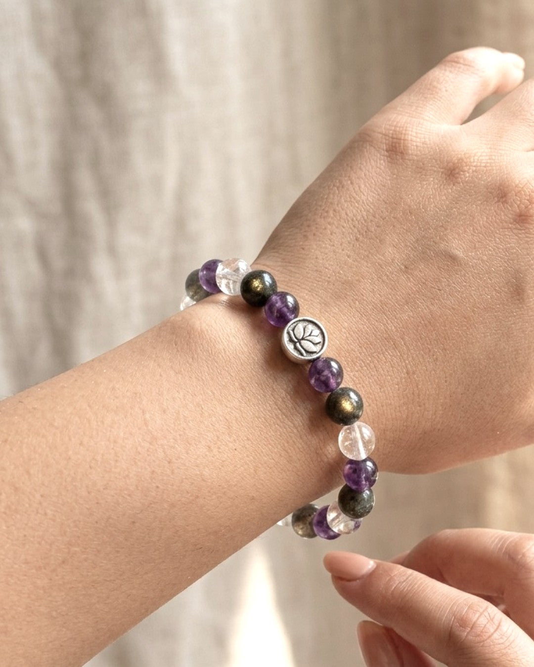 Amethyst, labradorite, and clear quartz lotus stretch bracelet worn on a wrist, silver lotus bead centered