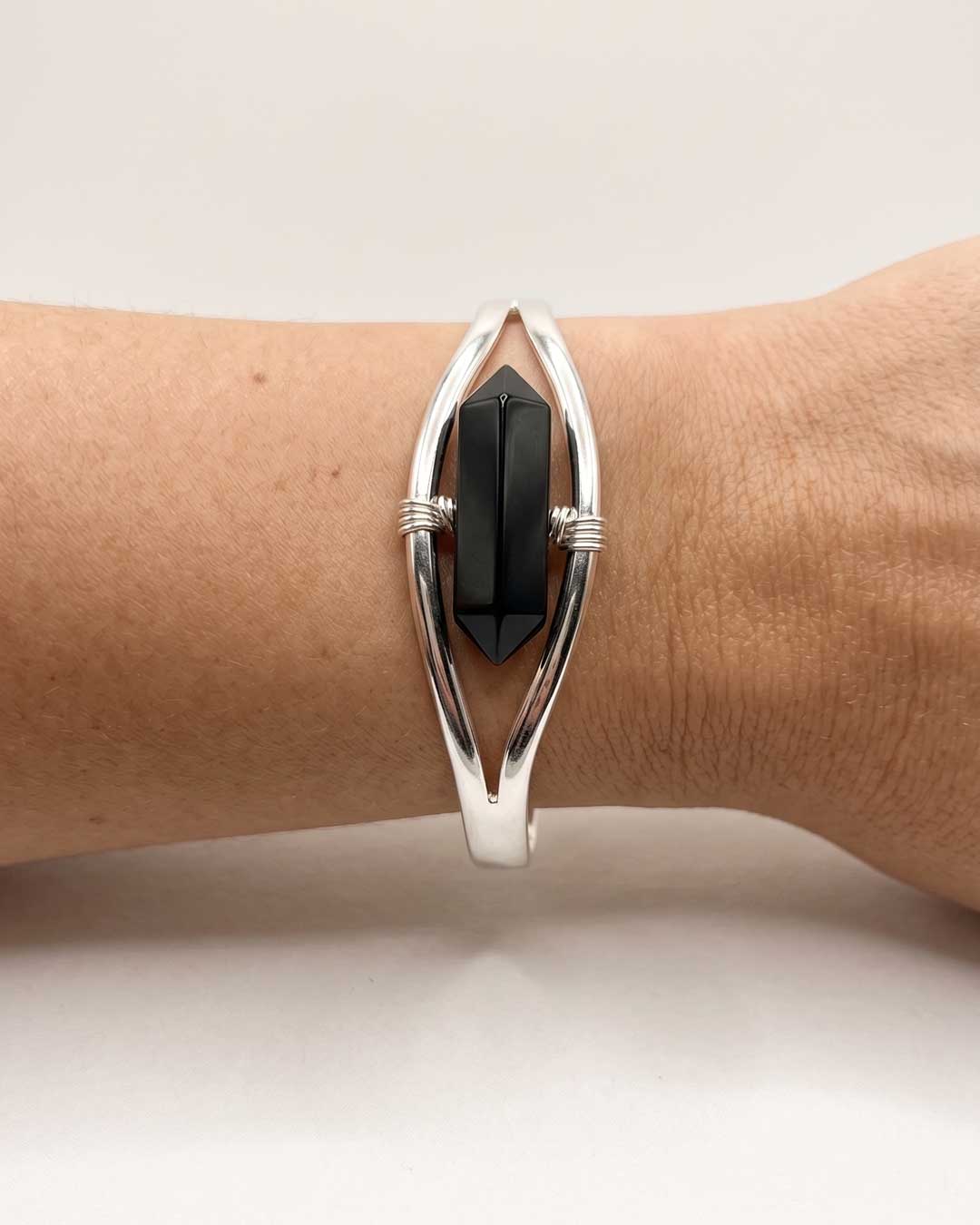 Close-up of silver black onyx point cuff bracelet worn on wrist showing the double-terminated stone in detail