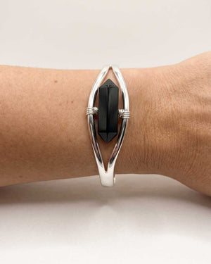 Close-up of silver black onyx point cuff bracelet worn on wrist showing the double-terminated stone in detail
