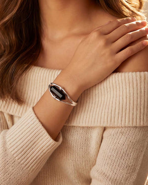 Woman wearing silver black onyx point cuff bracelet on wrist with off-shoulder cream sweater