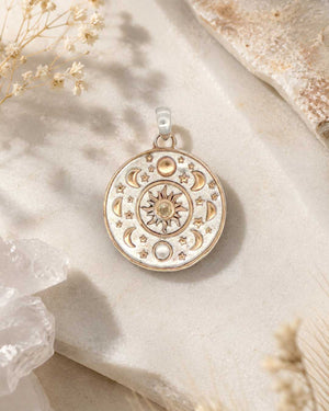Celestial Sun Moon Phases Pendant styled flat on textured stone surface with dried flowers and raw crystal props