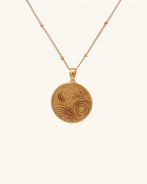 Gold plated brass lotus moon wave pendant hanging on a gold satellite chain, front view on white background