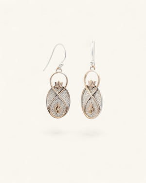 Infinite Lotus drop earrings angled view on white background, showing depth of the silver glitter oval body with bronze framing