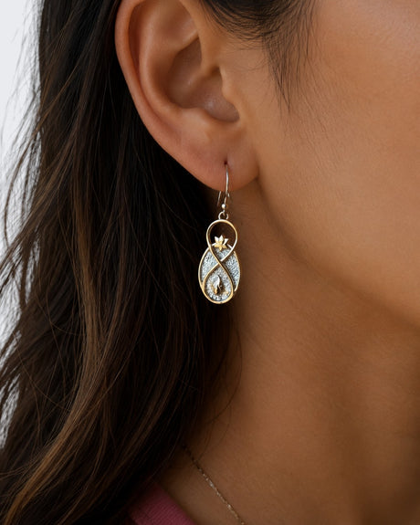 Infinite Lotus earring worn on model's ear, showing infinity-shaped bronze drop with lotus top and flame detail
