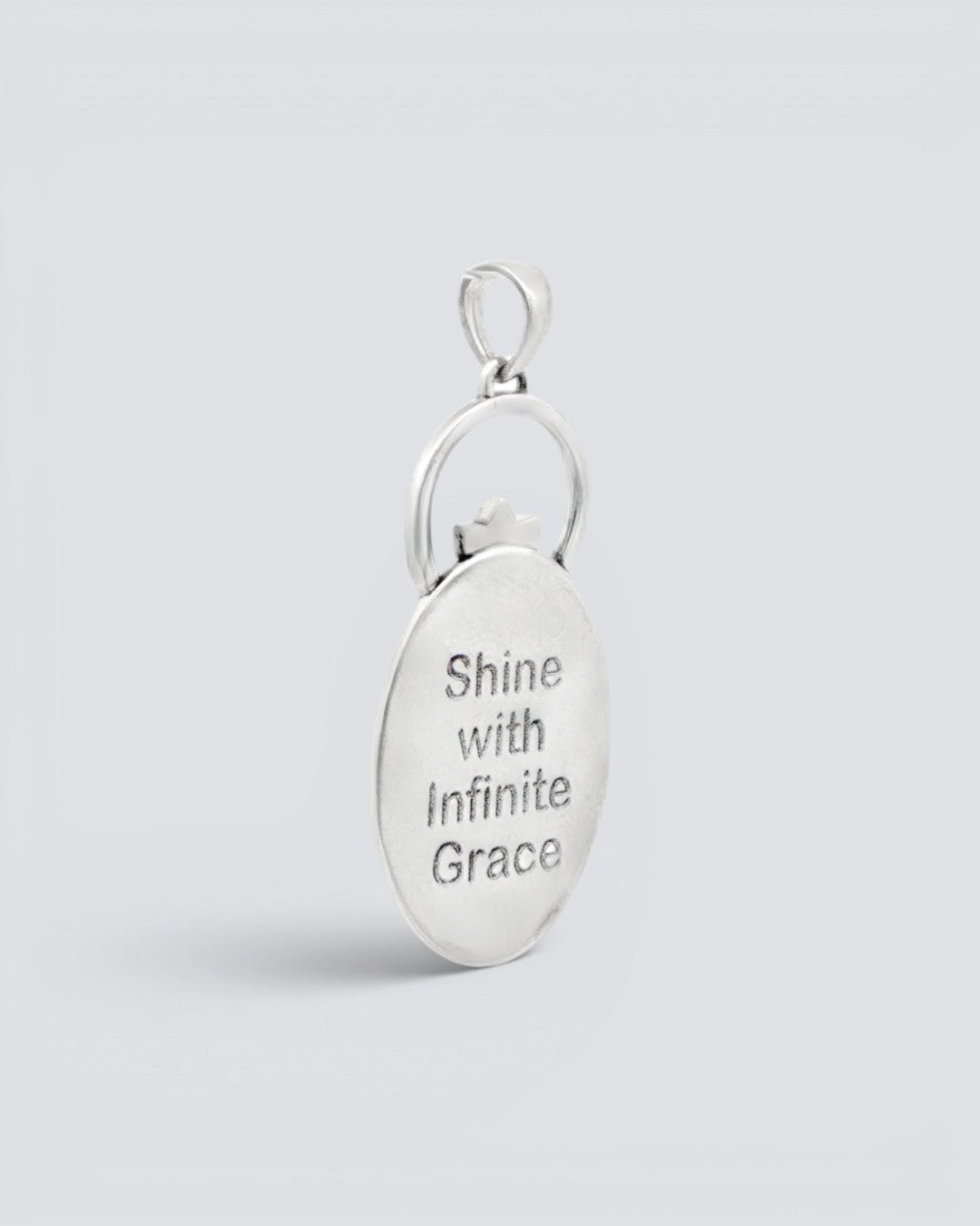 Back of the Infinite Lotus Flame Pendant silver charm engraved with the words Shine with Infinite Grace on a smooth oval surface