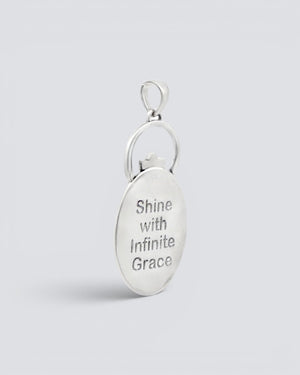 Back of the Infinite Lotus Flame Pendant silver charm engraved with the words Shine with Infinite Grace on a smooth oval surface