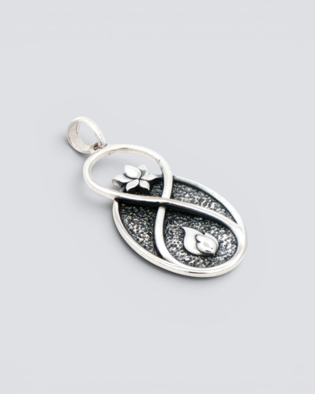 Infinite Lotus Flame Pendant silver charm viewed from an angled side perspective, showing the raised infinity frame and oxidized dark fill texture