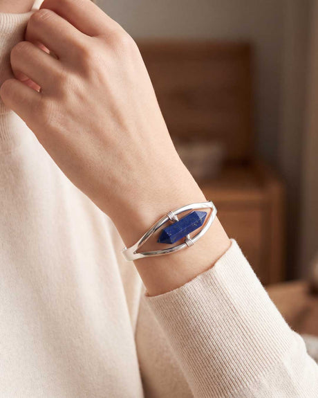 Woman wearing silver lapis lazuli point cuff bracelet on wrist with cream sweater