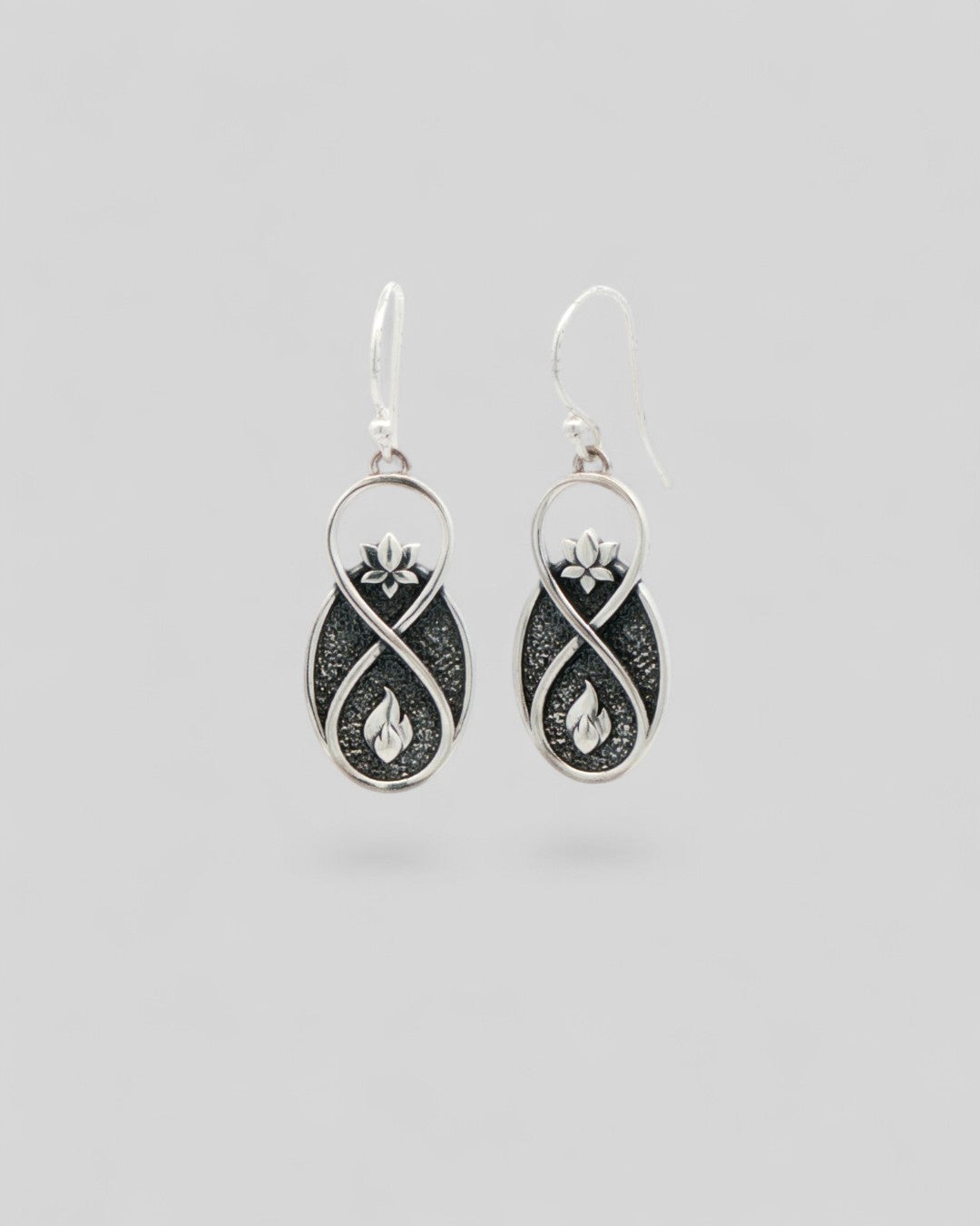 Lotus Infinity Flame silver drop earrings front view, showing oxidized infinity drop with raised lotus and flame symbols