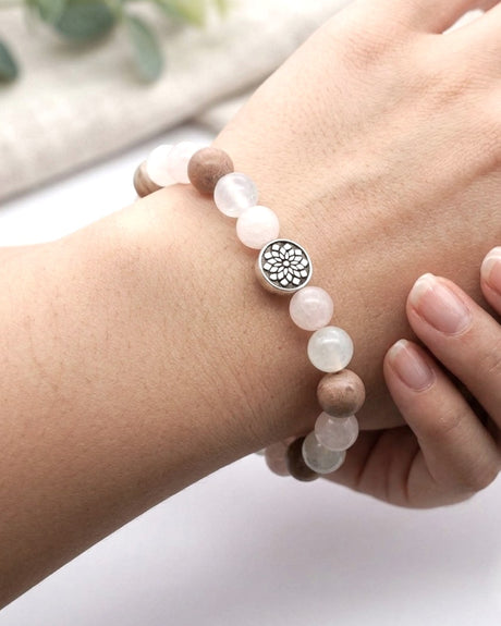 Mandala gemstone stretch bracelet worn on a wrist, silver mandala bead centered, soft neutral and botanical background