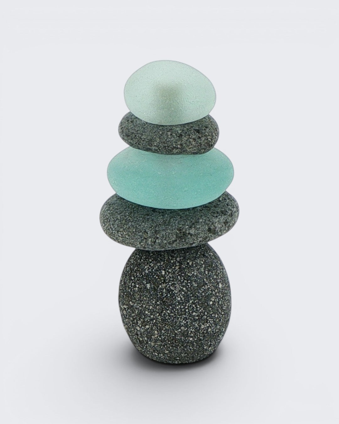 Single medium mini stacked stone cairn with alternating grey stones and teal sea glass pieces on a white background, front view