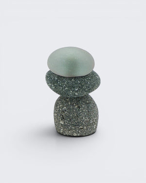Single small mini stacked stone cairn with a frosted sea glass top piece over two grey speckled stones, front detail view
