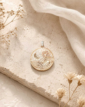 Moon and wave lotus pendant styled on a stone surface with dried flowers and sheer fabric in the background