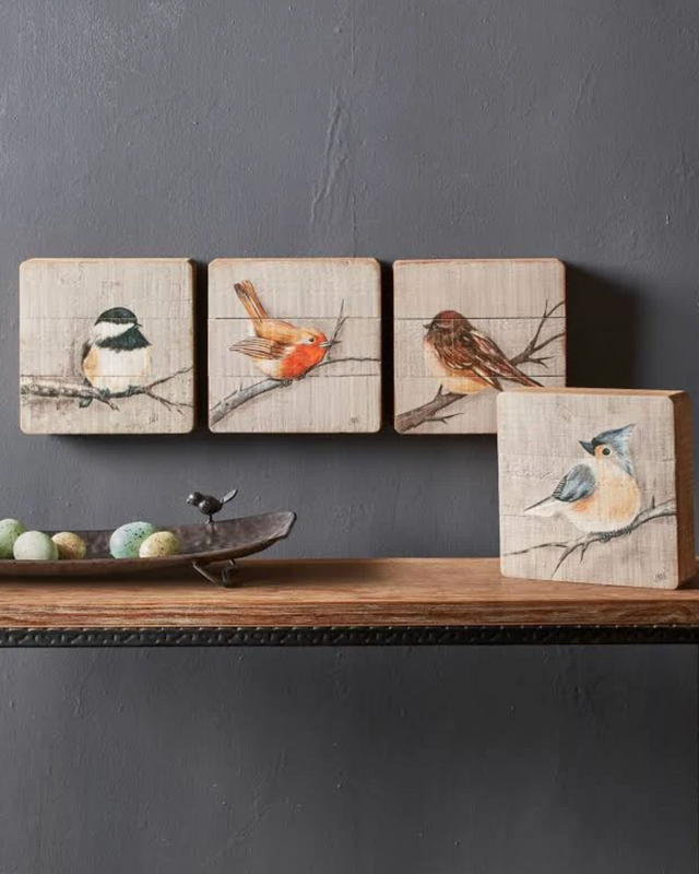 Set of 4 rustic wood songbird plaques arranged on a wooden shelf with a small bird figurine and egg-shaped accents