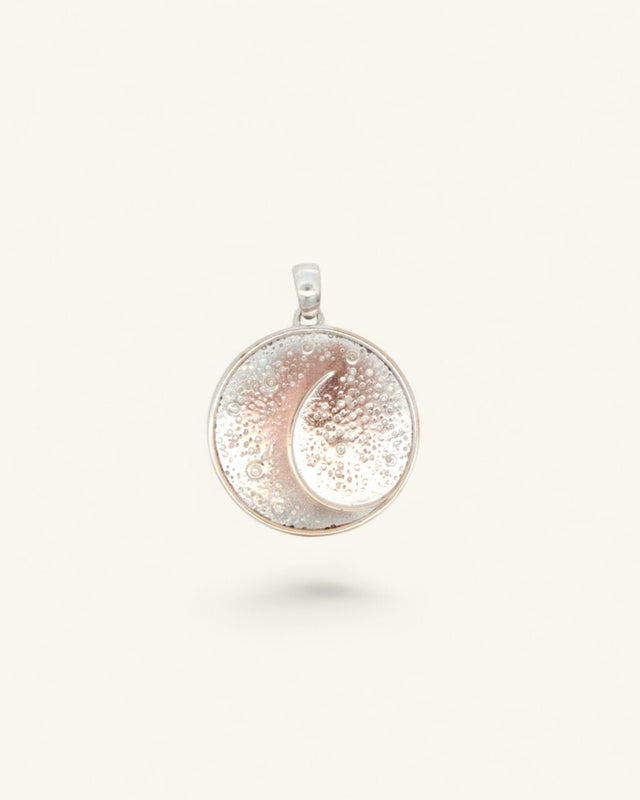 Silver-plated crescent moon pendant, round disc face with textured star field and rose-gold toned moon, front view