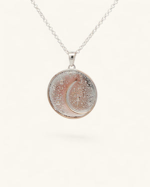 Silver-plated celestial crescent moon pendant hanging on a silver rolo chain against a light background