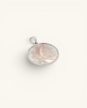 Silver-plated crescent moon pendant shown at a slight side angle, revealing the round disc profile and bezel edge
