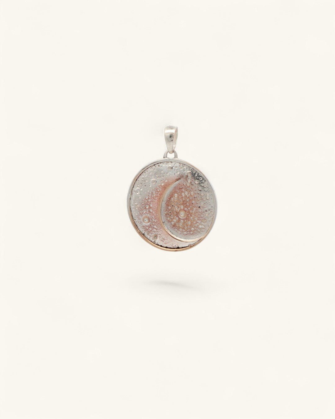 Silver-plated crescent moon pendant at a three-quarter angle showing the textured disc face and silver bail loop