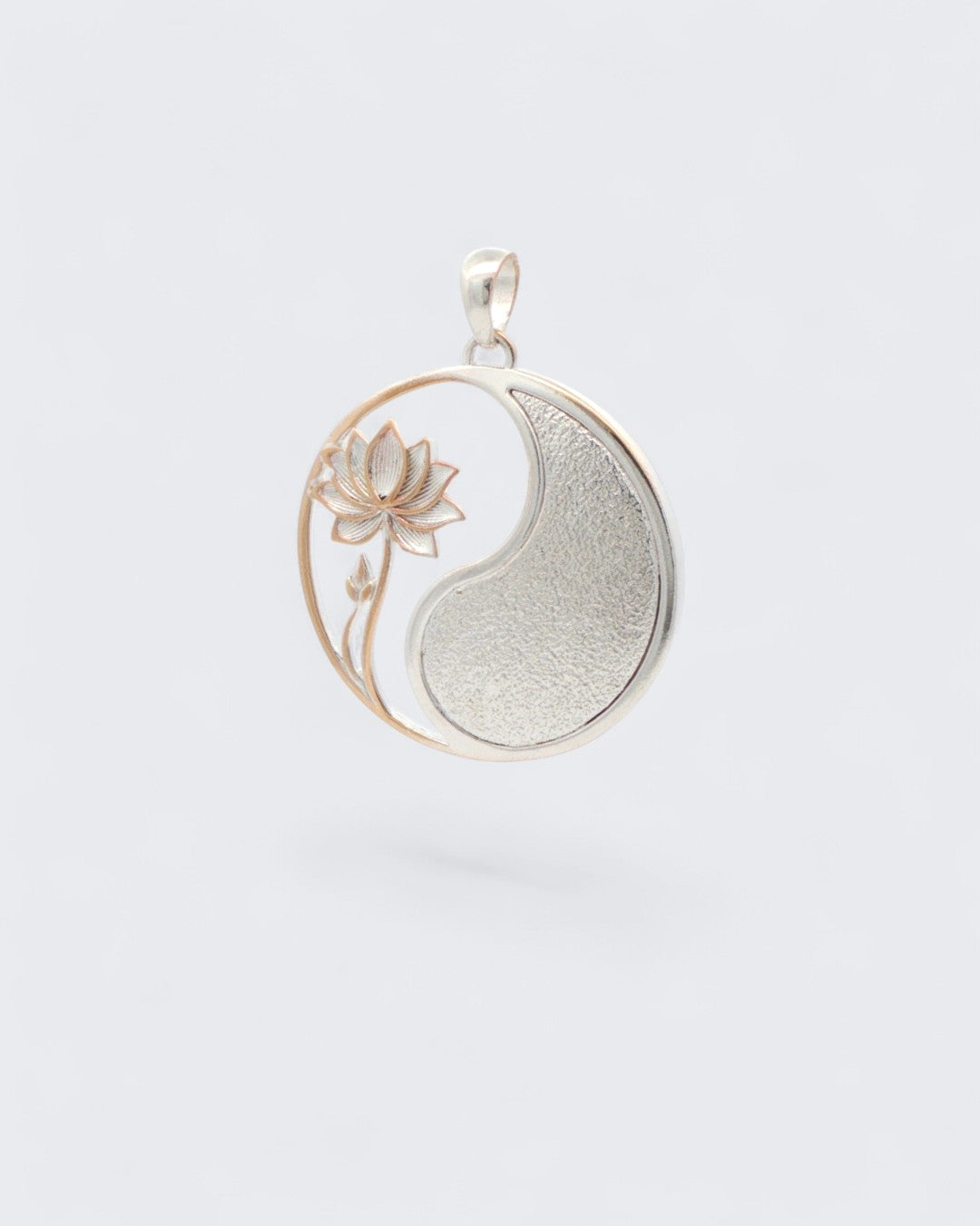 Yin yang lotus pendant tilted at an angle showing the rose gold lotus stem detail and the curved silver yang portion and bail