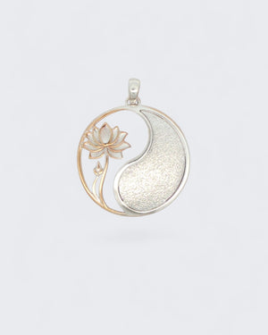 Yin yang lotus pendant front view on neutral gray background showing open rose gold lotus cutout and textured silver yang fill